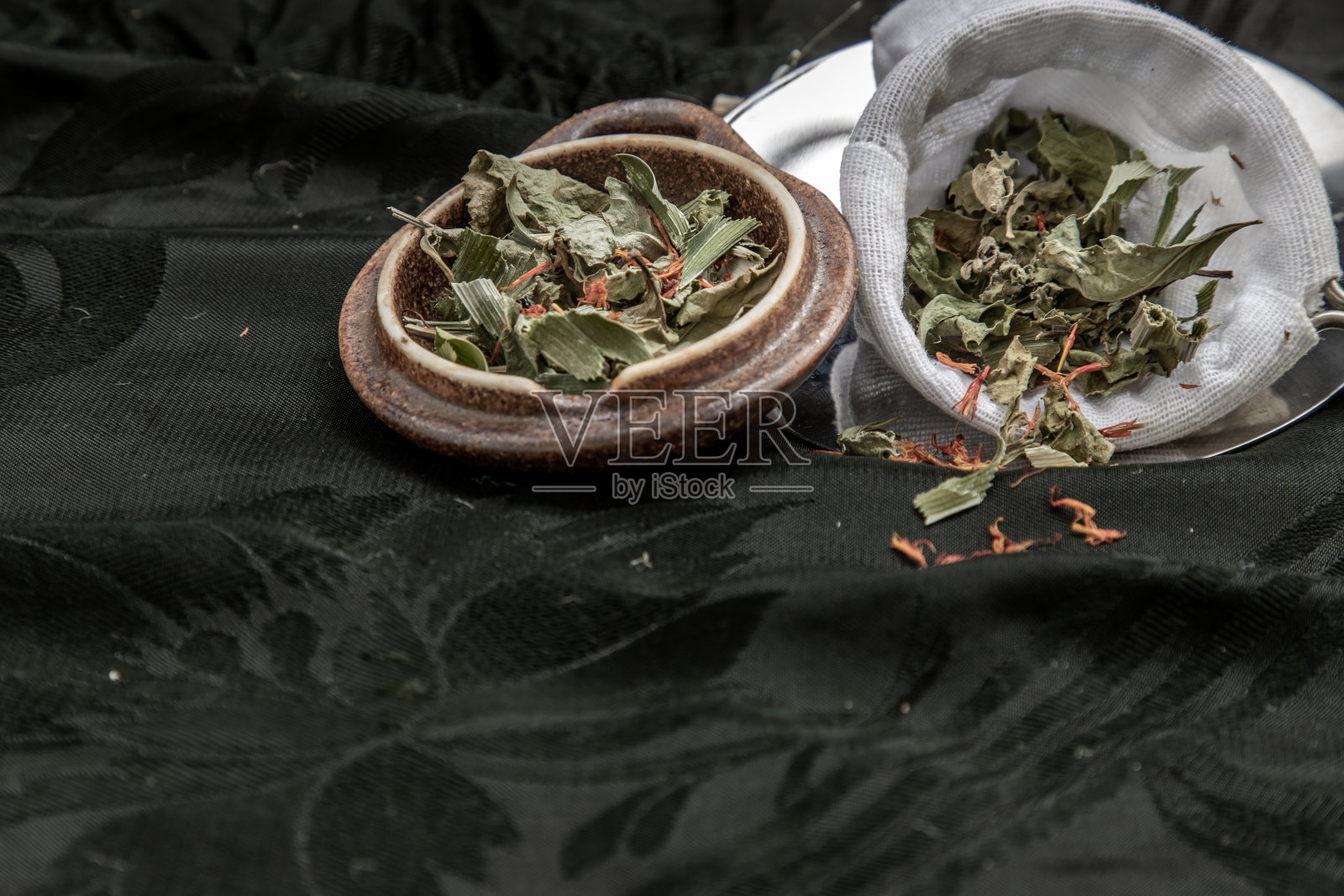 干的香兰叶子，印度沼泽飞蓬植物的叶子与红花干(藏红花替代品)在黑暗的背景。照片摄影图片