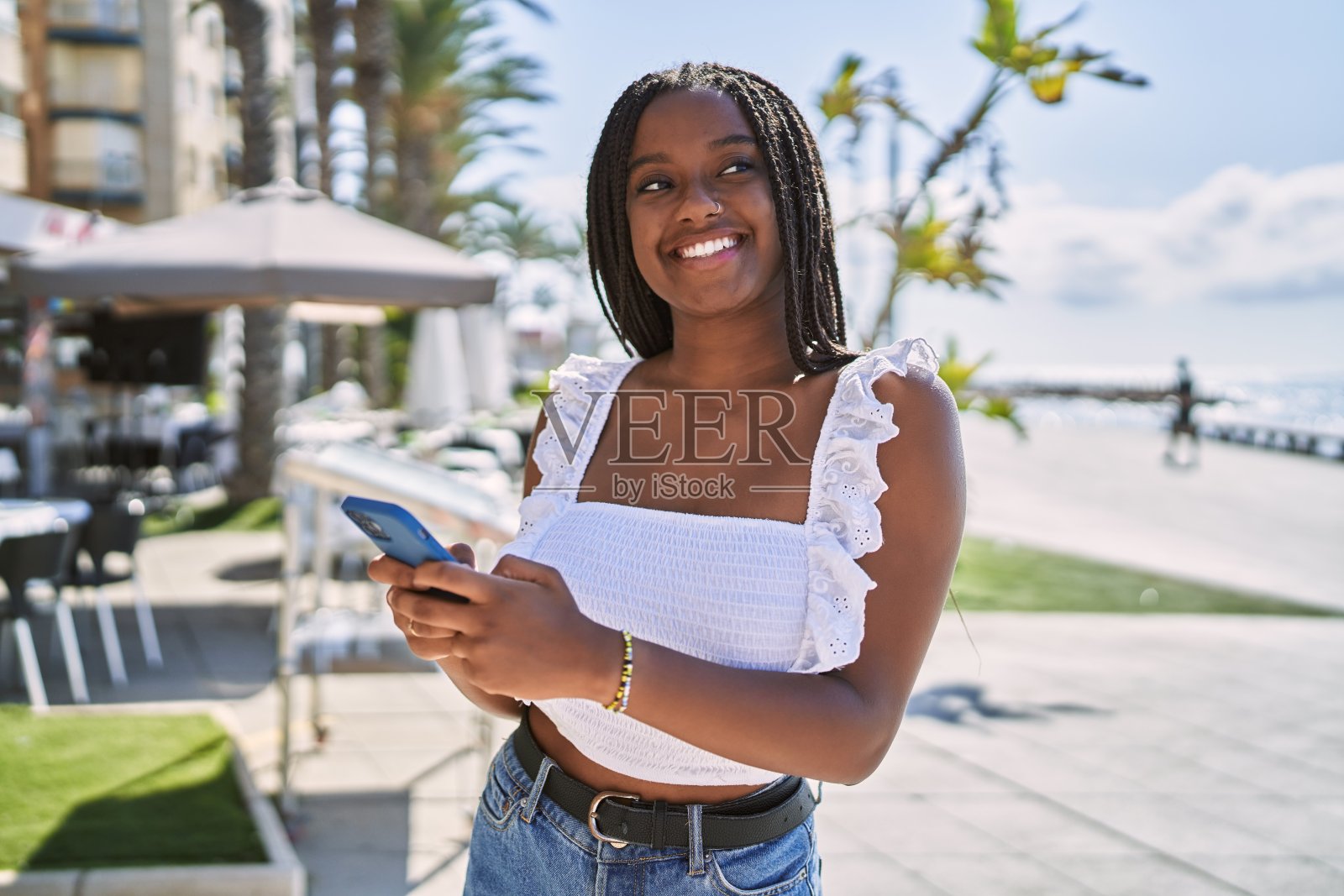 年轻的非洲裔美国女孩微笑快乐地使用智能手机在长廊照片摄影图片