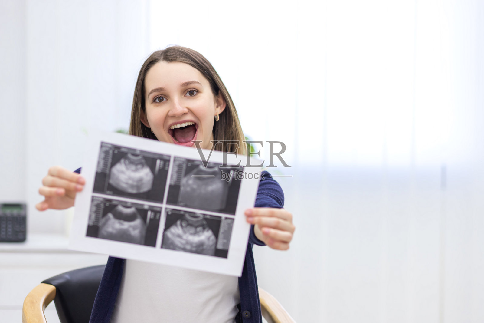 微笑的孕妇手持超声结果的照片。照片摄影图片