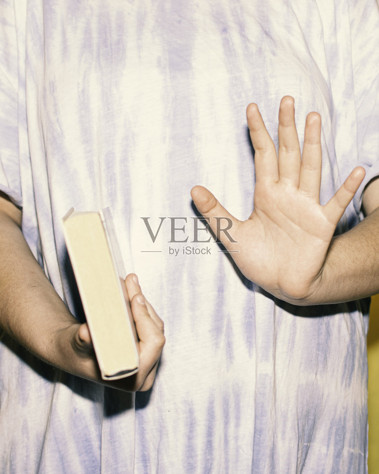 一个女人穿着扎染衬衫，手里拿着一本书，举起手掌照片摄影图片