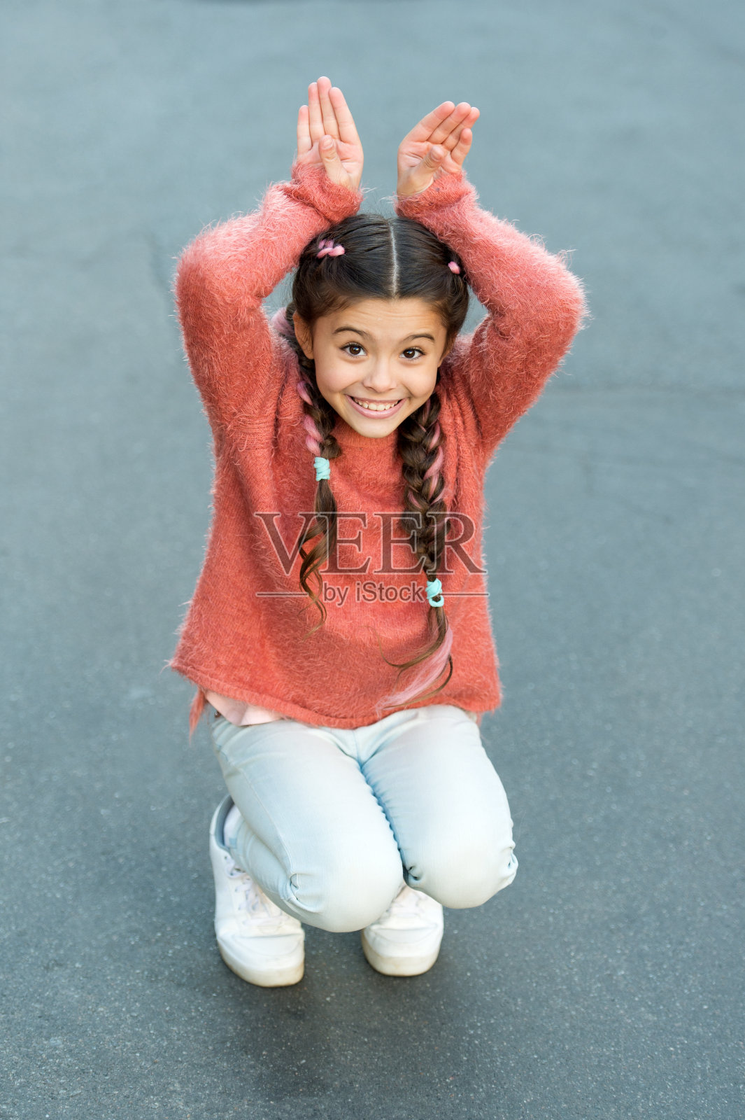 复活节快乐。假日兔女郎的姿势像兔子灰色的背景。孩子微笑着扮演兔子的角色。顽皮的宝宝庆祝复活节。春天的假期。天赋和表演。快乐的童年。可爱的兔子照片摄影图片