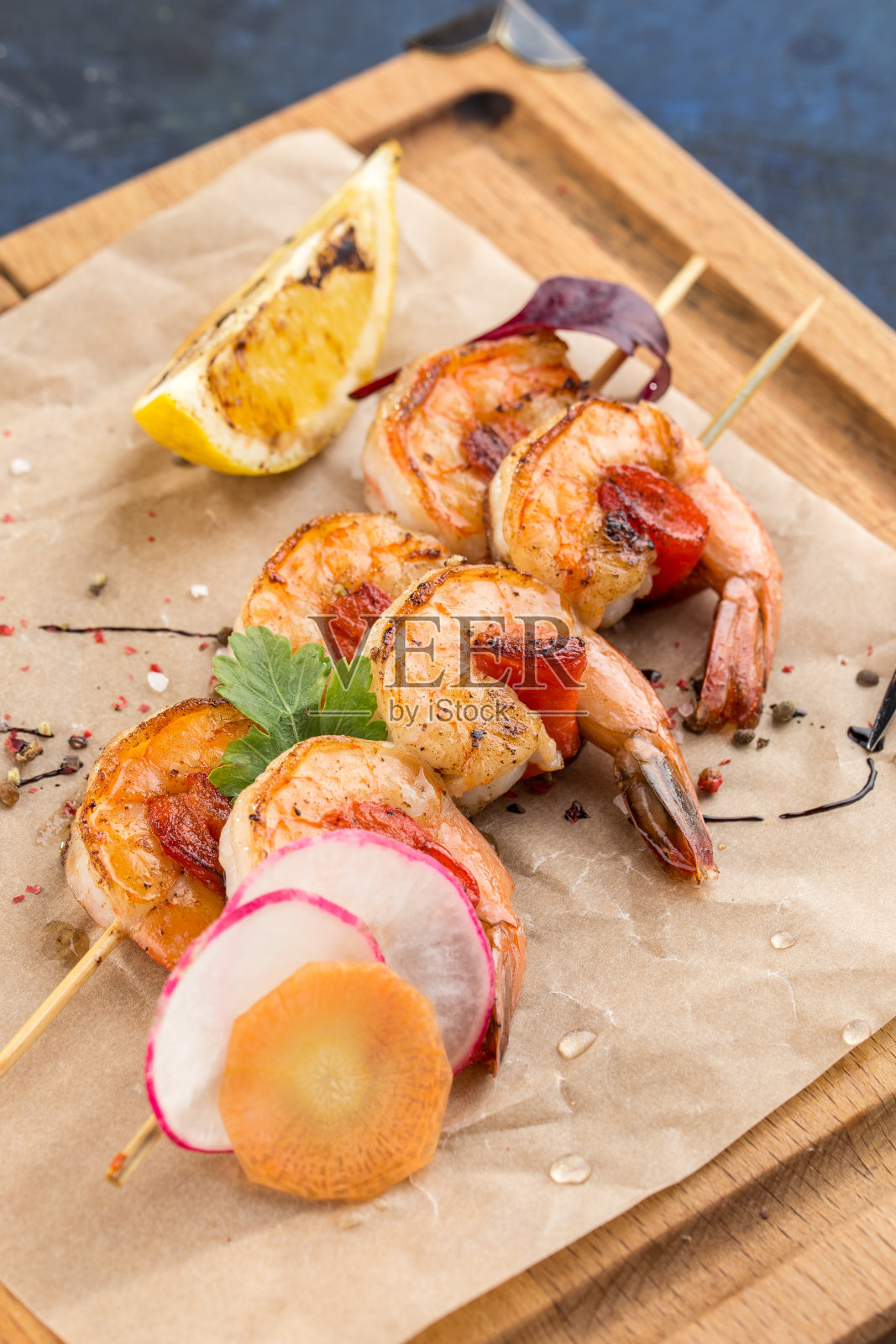 烤对虾串虾和柠檬片木板上的蓝色背景照片摄影图片