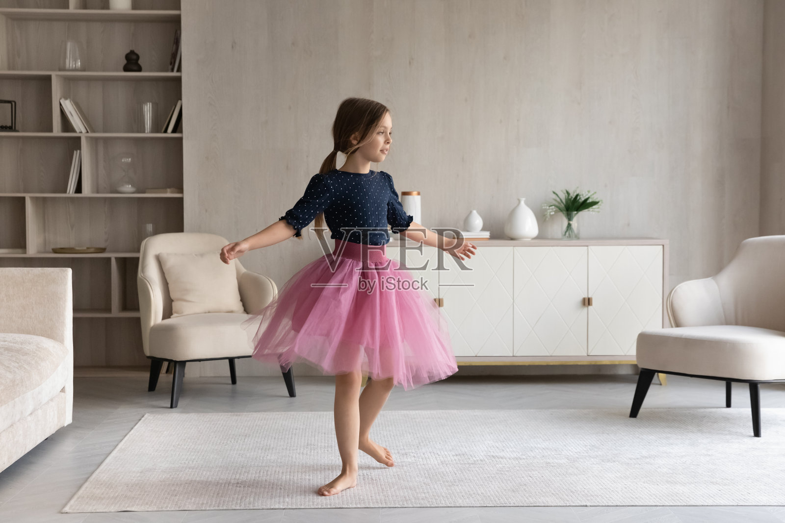 在现代客厅里跳舞的快乐小女孩照片摄影图片