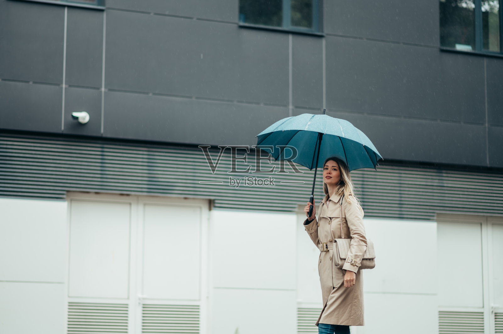 女商人打着伞在雨中走在城市街道上照片摄影图片