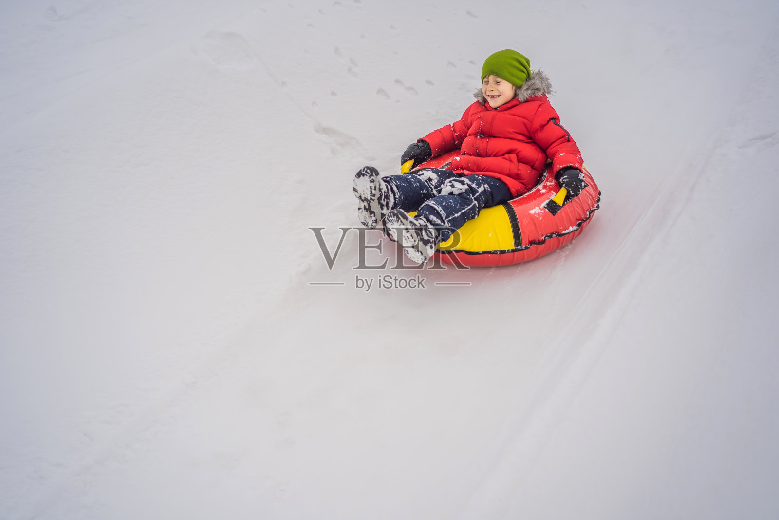 孩子在雪地上玩得很开心。男孩骑着一根管子。孩子们的冬季乐趣照片摄影图片