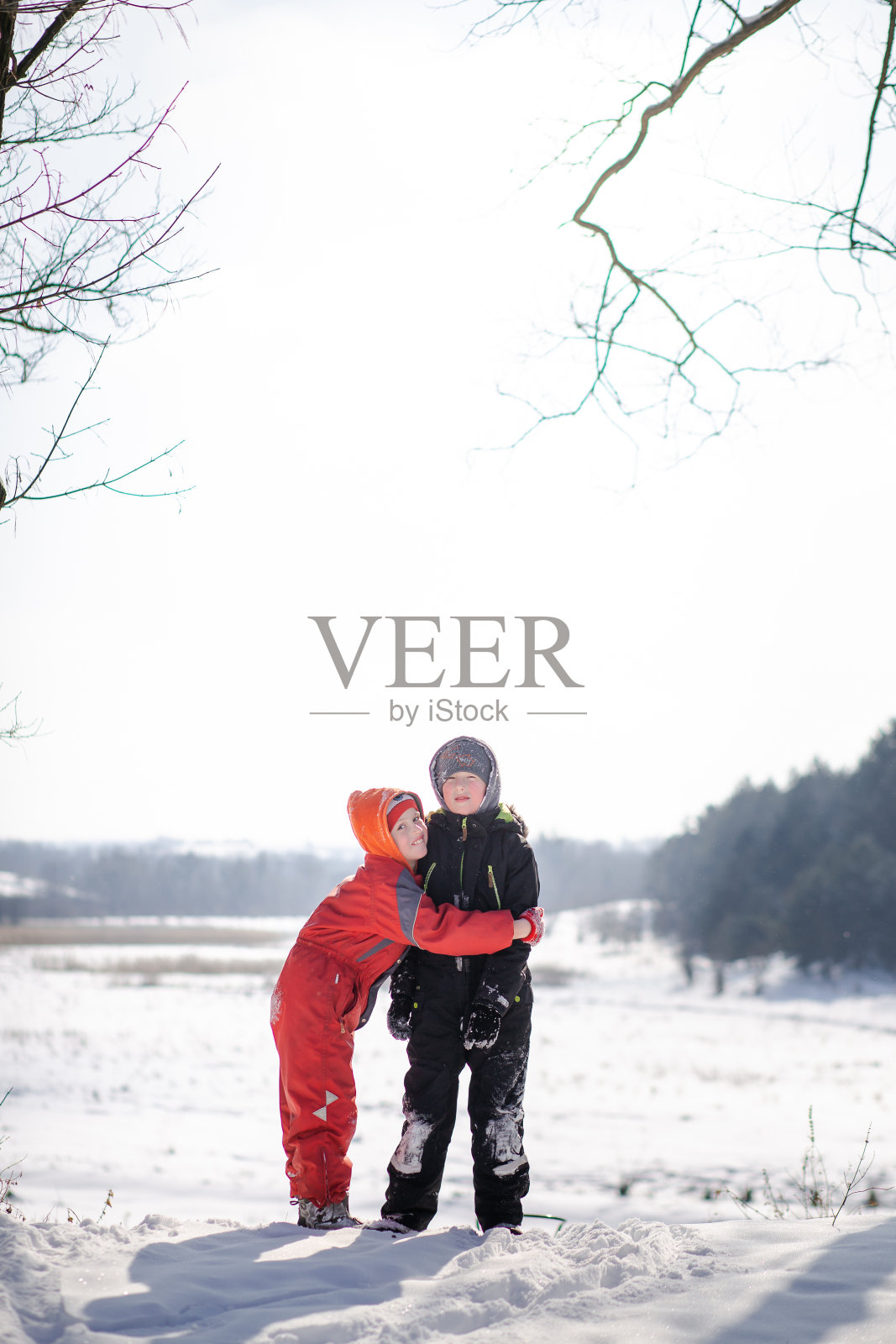 一个穿着滑雪服的男孩在雪山上拉着雪橇。这个孩子正在骑一辆雪橇小摩托车。活跃的游戏在街上。健康的生活方式照片摄影图片