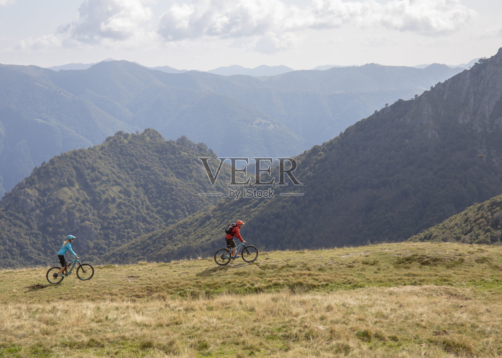 山地自行车手沿着长满草的山脊行进照片摄影图片