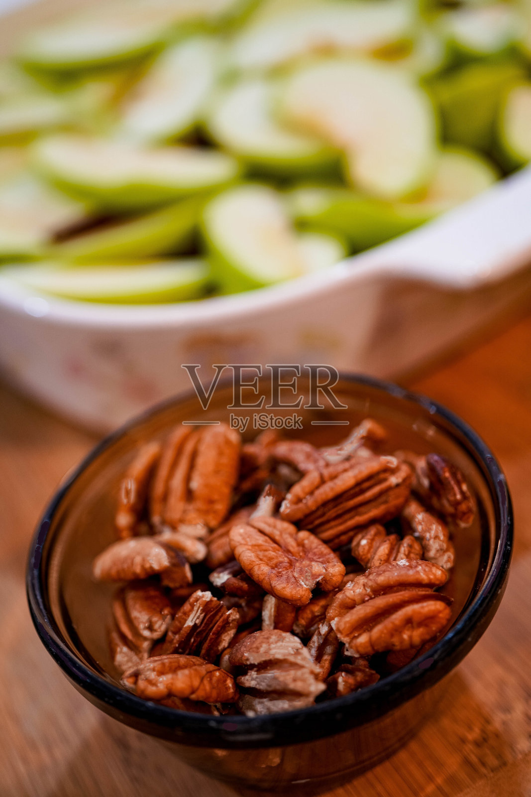 山核桃放在切片苹果前，选择性聚焦照片摄影图片