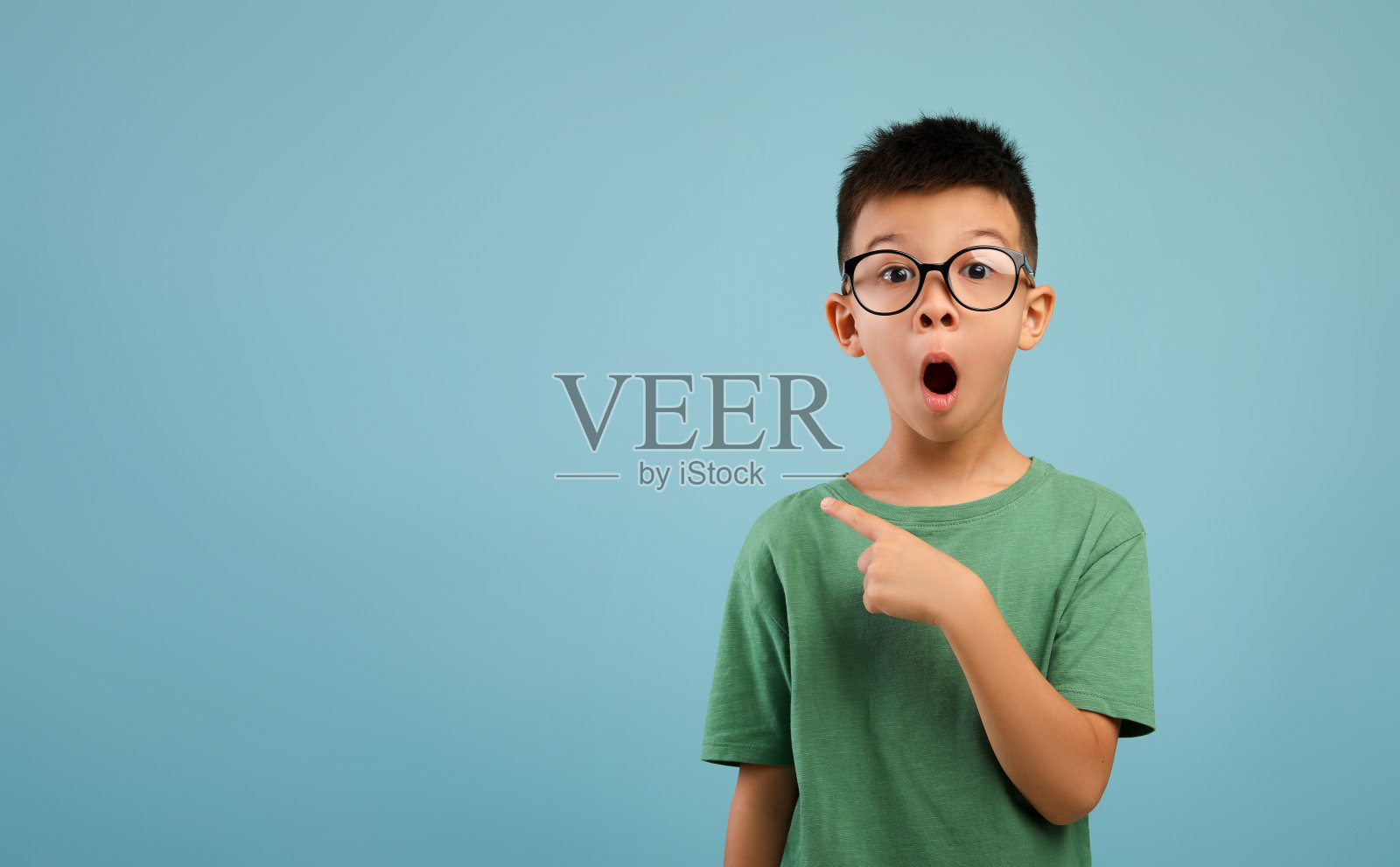 神奇的报价。兴奋的亚洲男孩戴着眼镜指着旁边的复印空间照片摄影图片