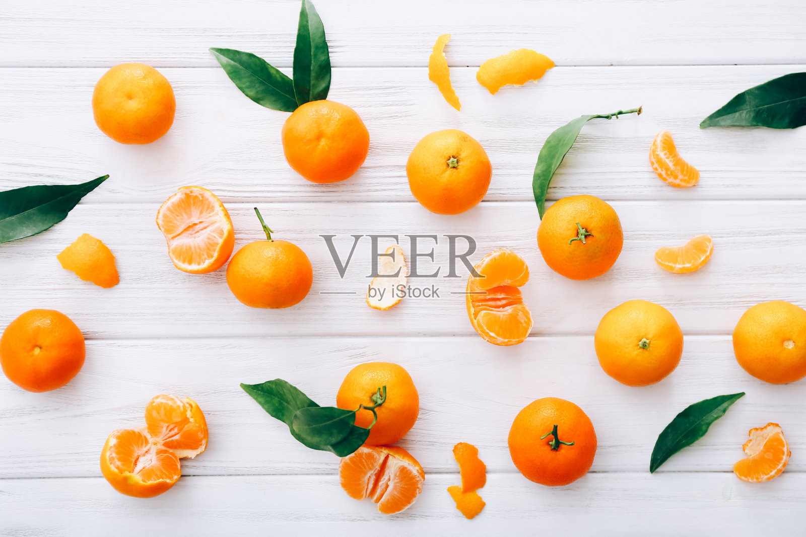 白色木桌上放着带叶子的新鲜小柑橘。照片摄影图片