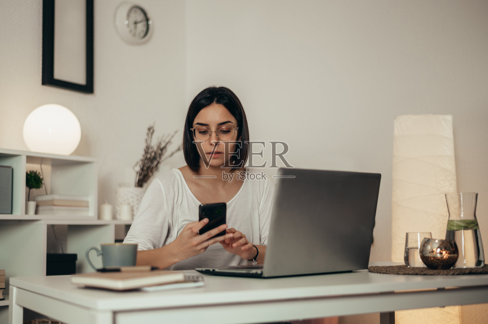 漂亮的女人在家工作时用智能手机和笔记本电脑照片摄影图片