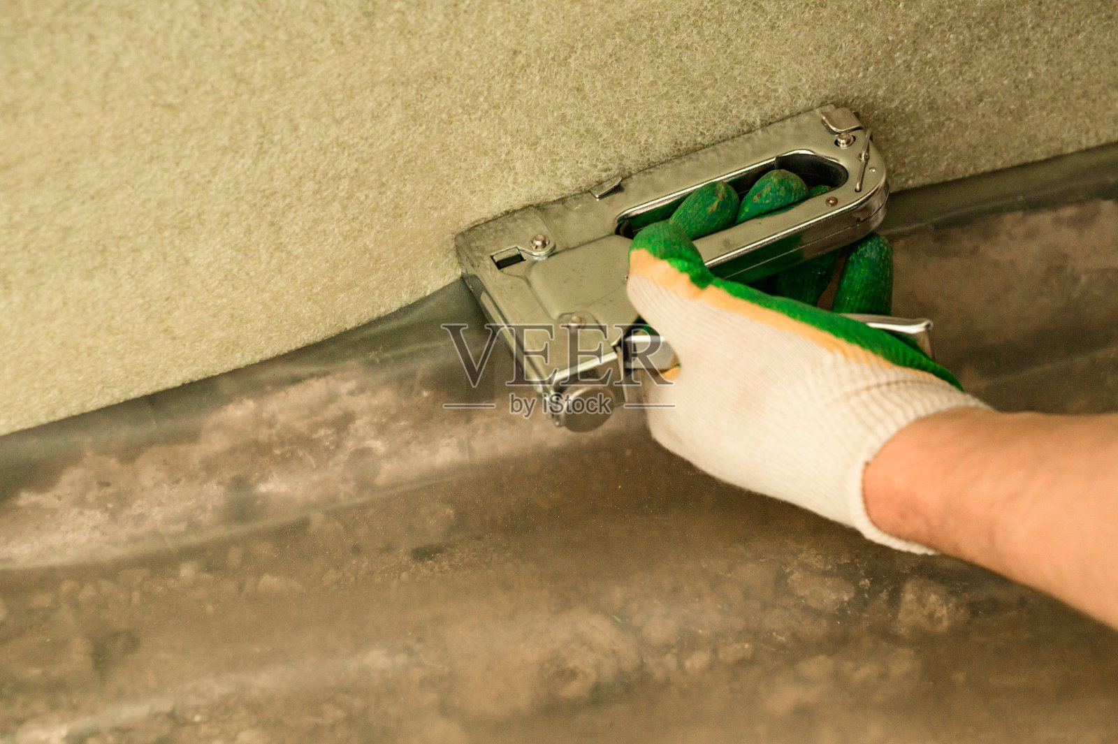 这名男子将阻尼胶带粘在墙底，以保护地板耦合器。照片摄影图片