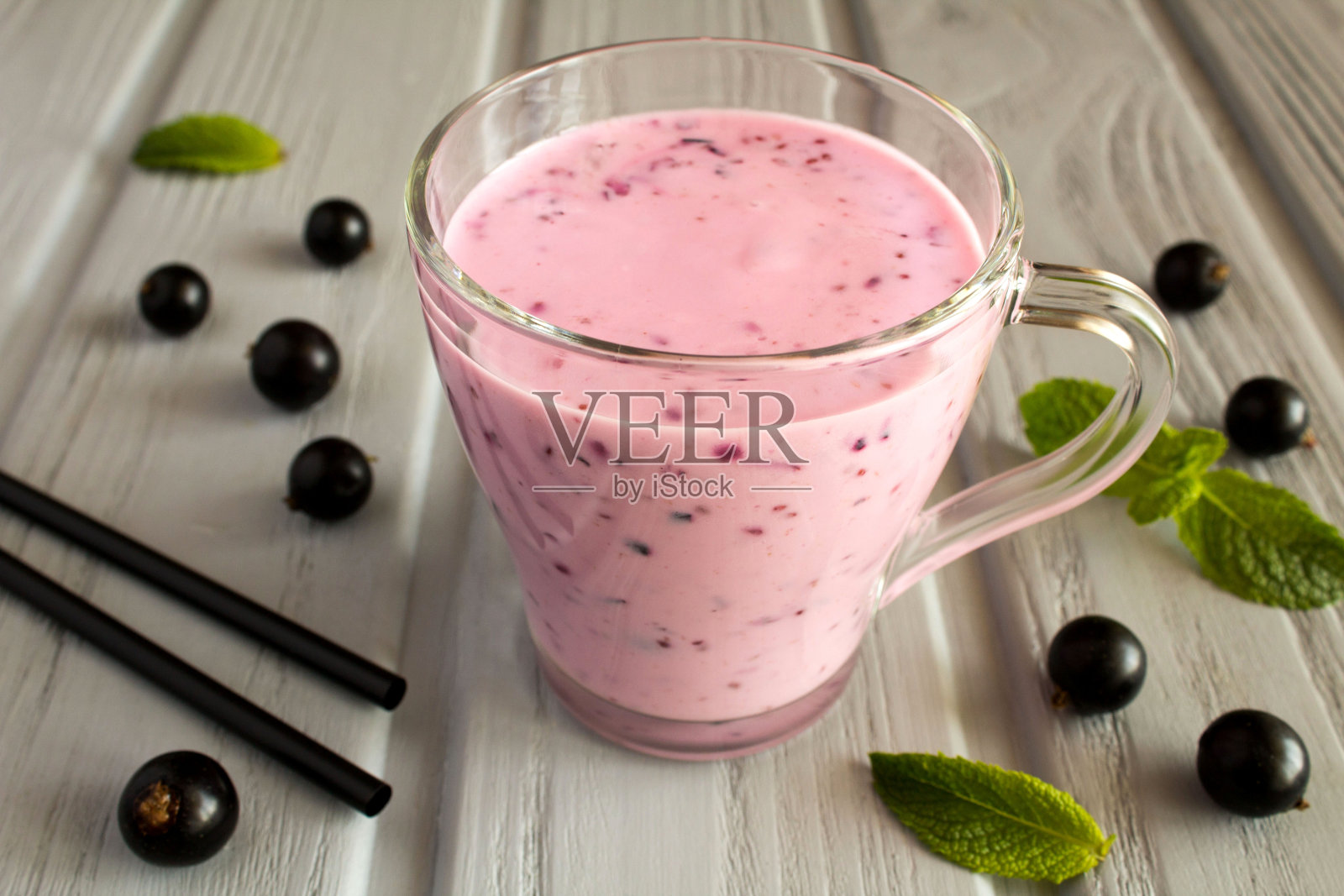 酸奶冰沙配黑醋栗在灰色木制背景的玻璃杯里。特写镜头。照片摄影图片