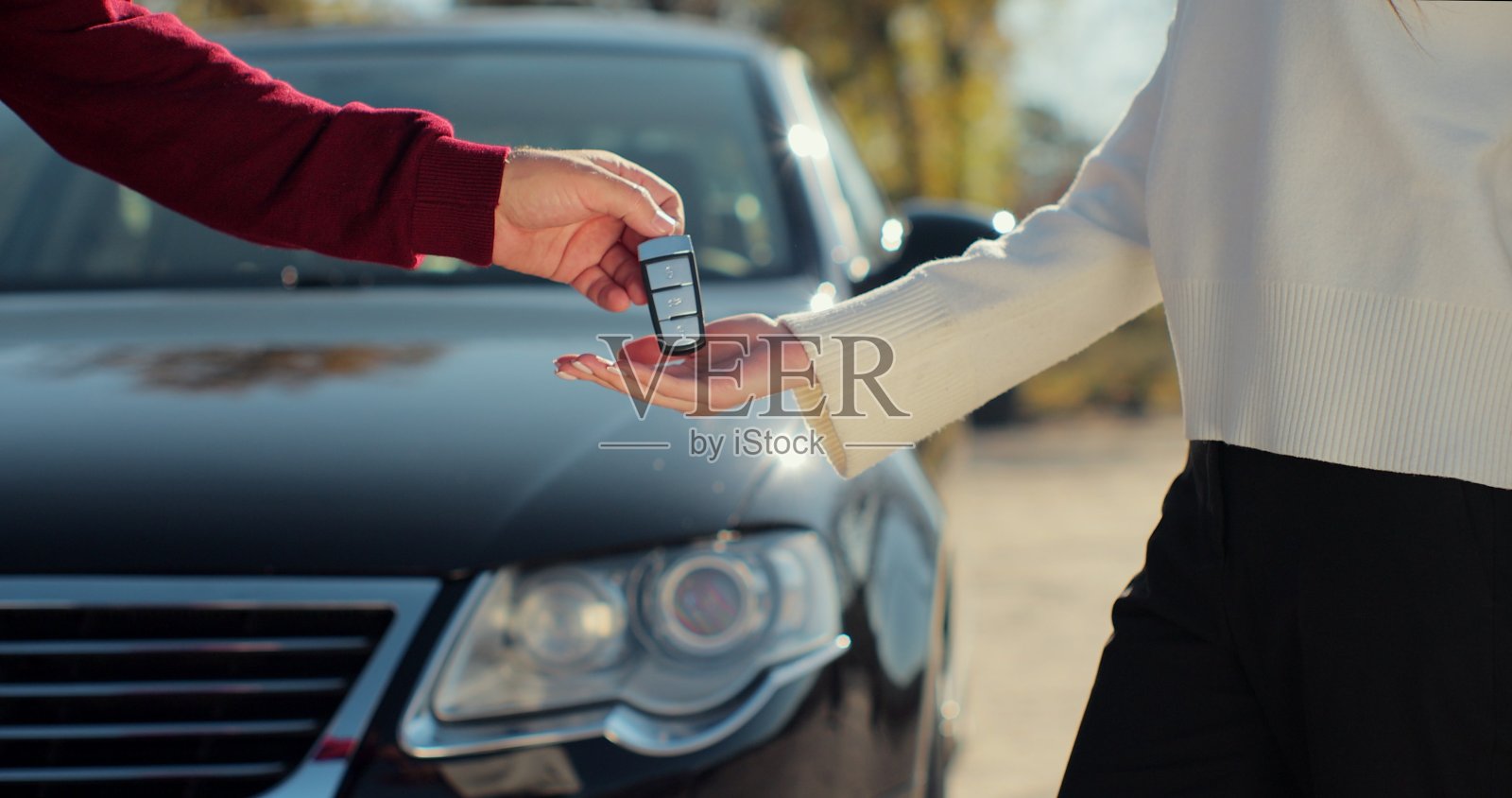 男人把车钥匙递给女人在汽车经销店关门。一个不知名的汽车销售商和一个买车的女人。在车展或沙龙给新主人钥匙的经销商。照片摄影图片