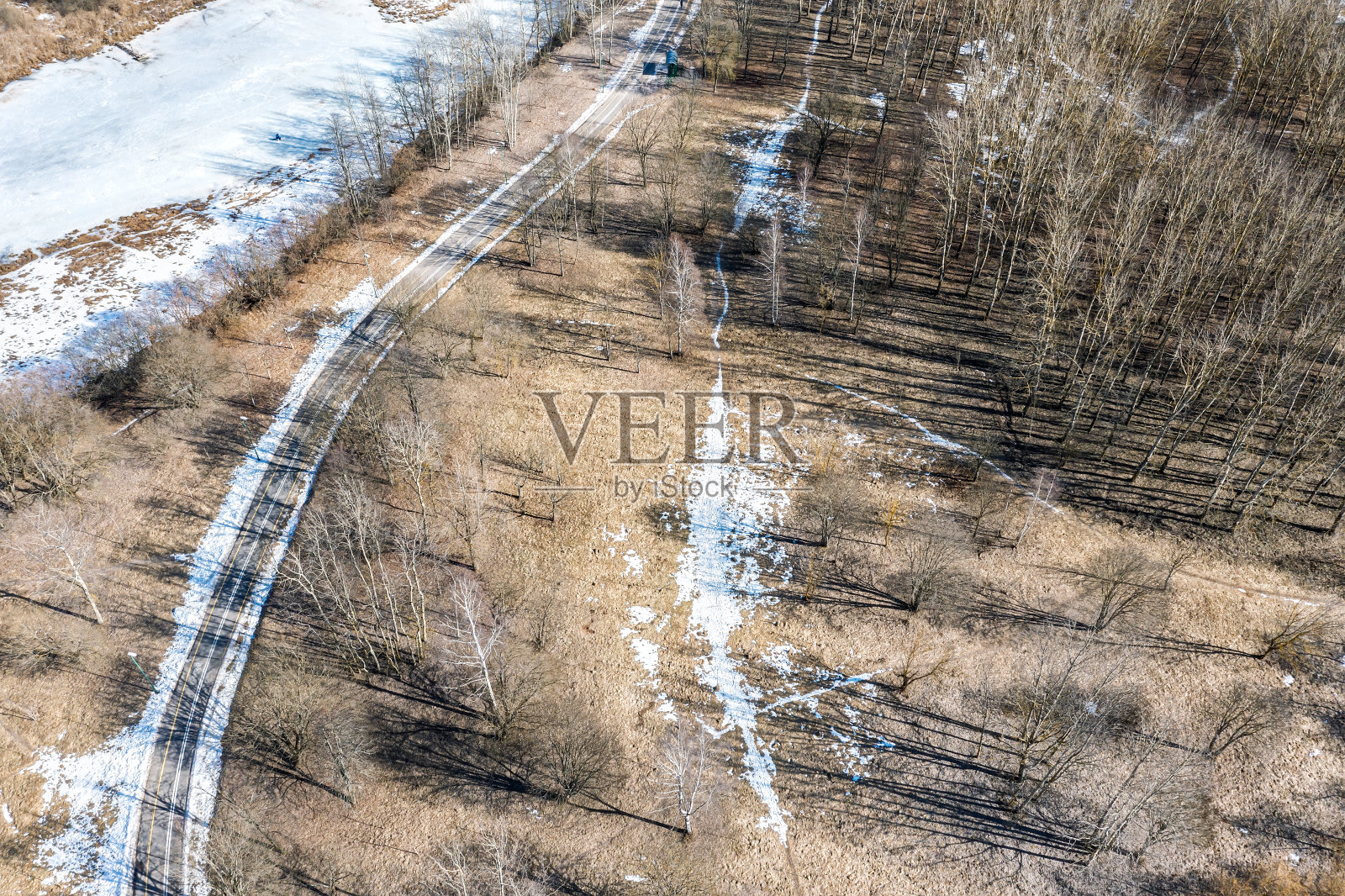 阳光明媚的冬季公园景观。蜿蜒的自行车道沿河而过。鸟瞰图。照片摄影图片