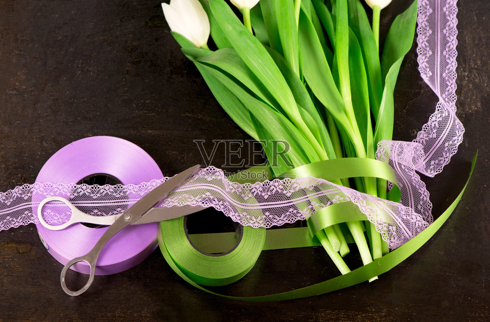 俯瞰美丽的郁金香花束在包装纸里，木桌上的缎带和旧剪刀照片摄影图片