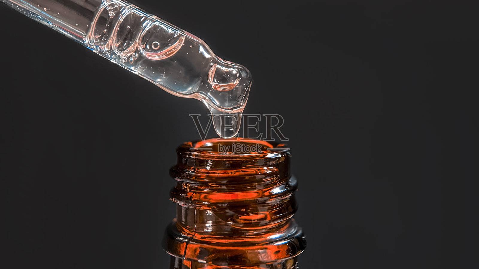 移液管与一滴面部血清或油的脸和透明质酸在美丽的黑色背景，特写照片摄影图片