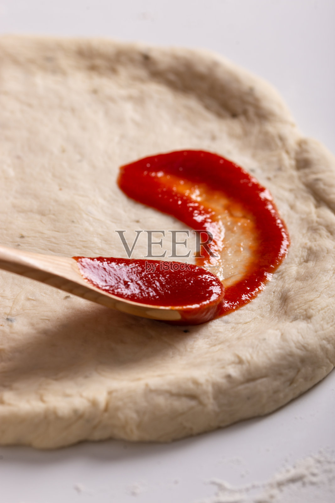 做披萨的过程，把番茄酱放在面团上照片摄影图片