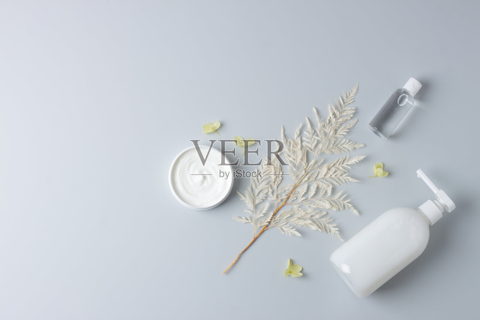 在灰色背景上有花的化妆品护肤品。平铺，复制空间照片摄影图片
