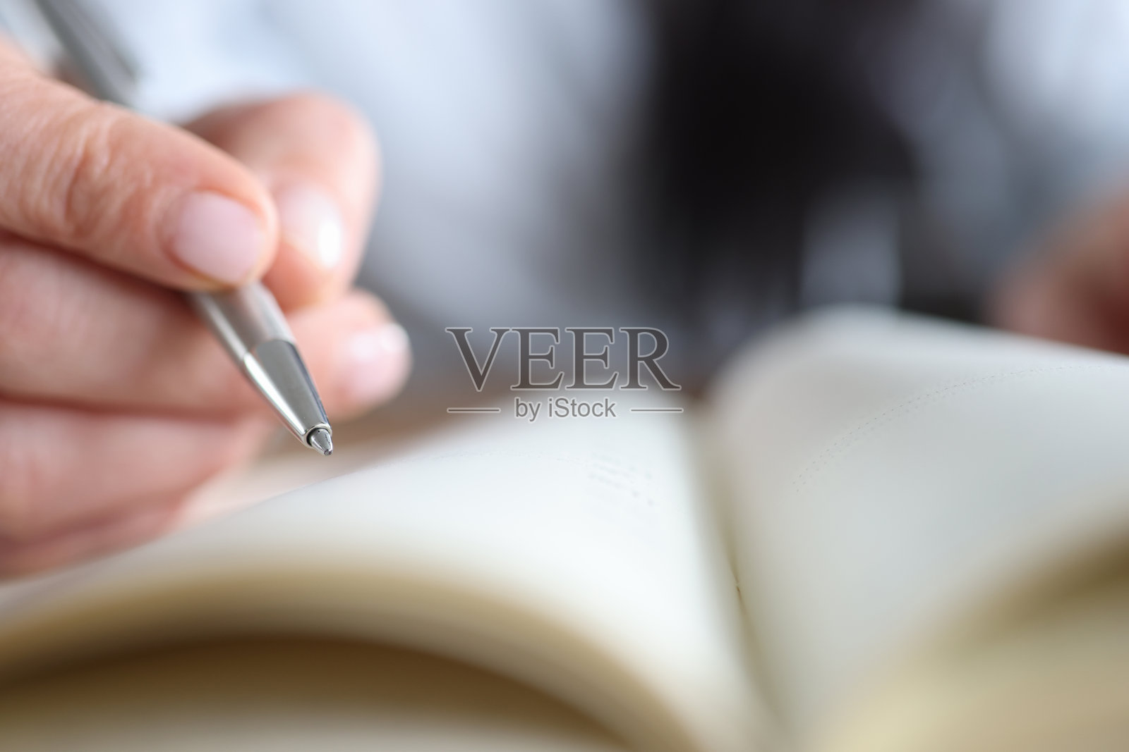 一个女人的手在笔记本旁边拿着笔，特写镜头照片摄影图片