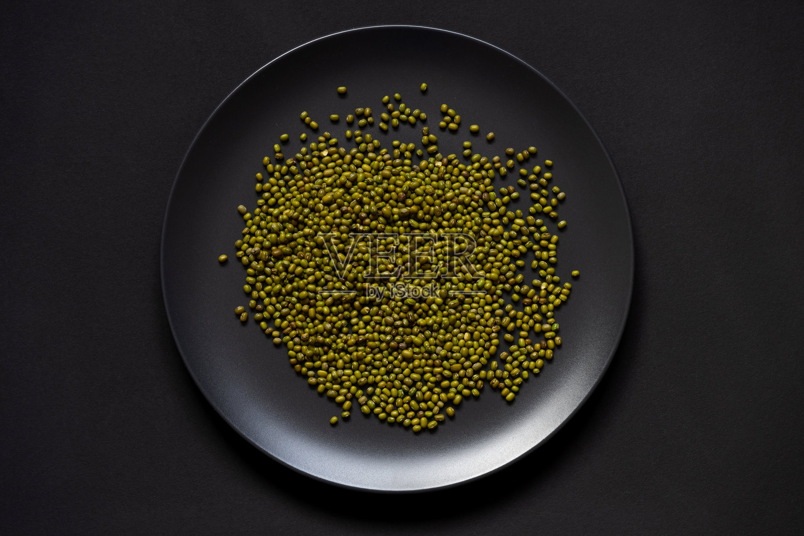 黑色盘子里装着大量绿豆。照片摄影图片