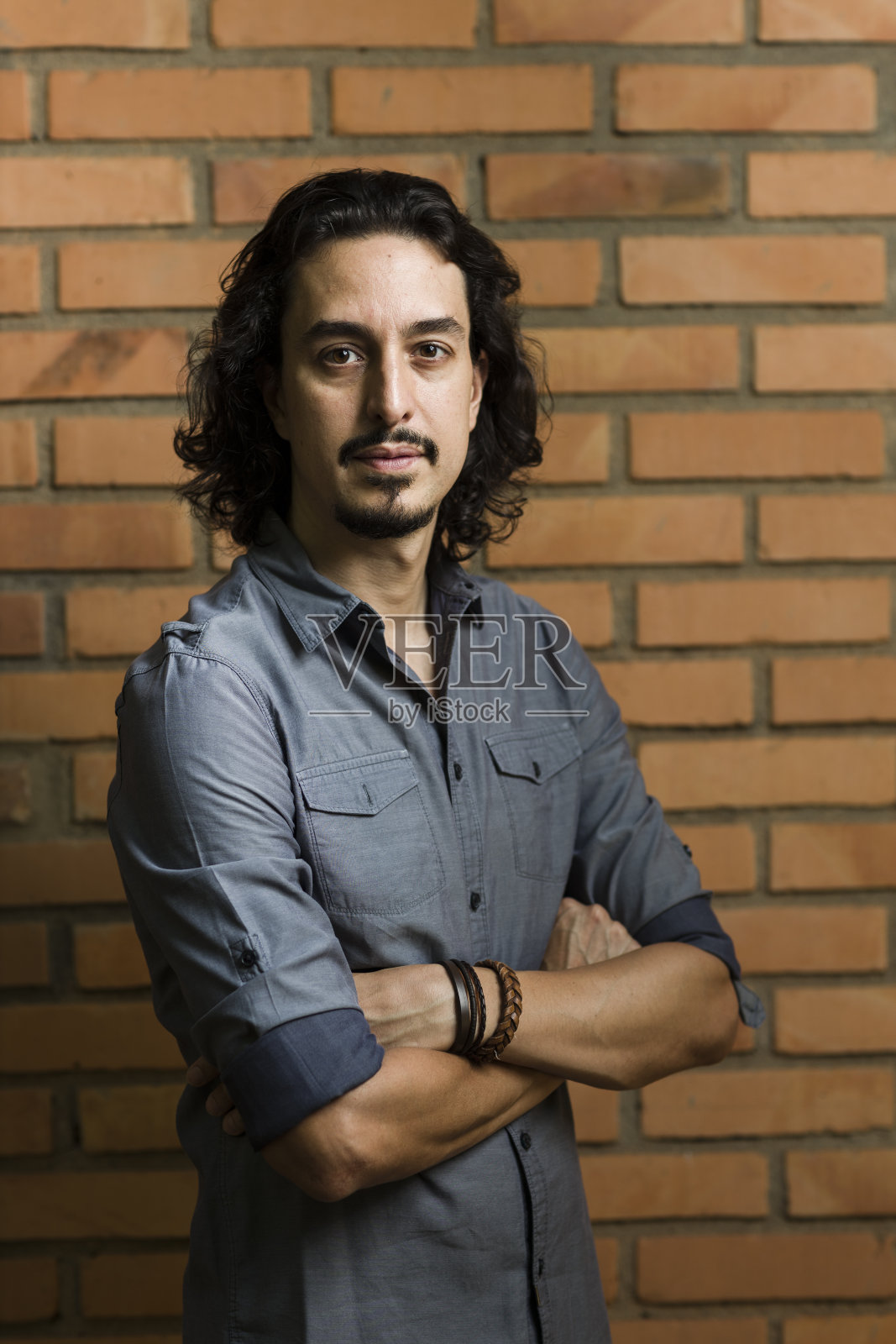 穿蓝衬衫的男人在砖墙前的肖像照片摄影图片