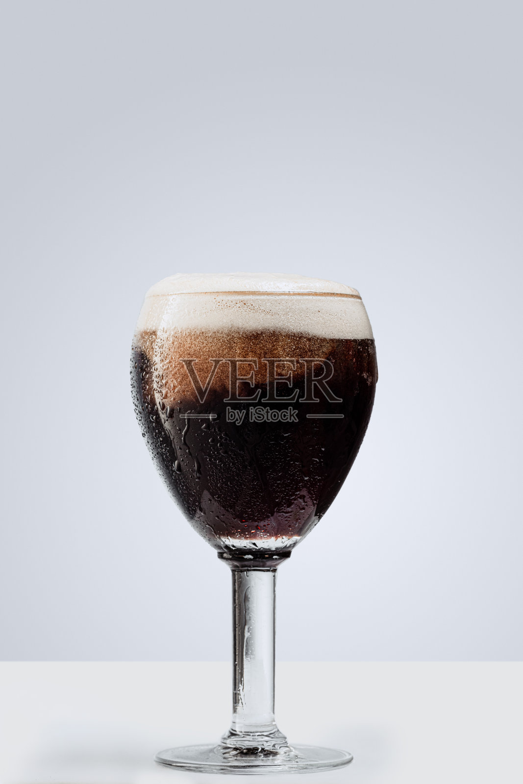 一杯深色泡沫啤酒孤立在灰色背景。酒的概念，派对照片摄影图片