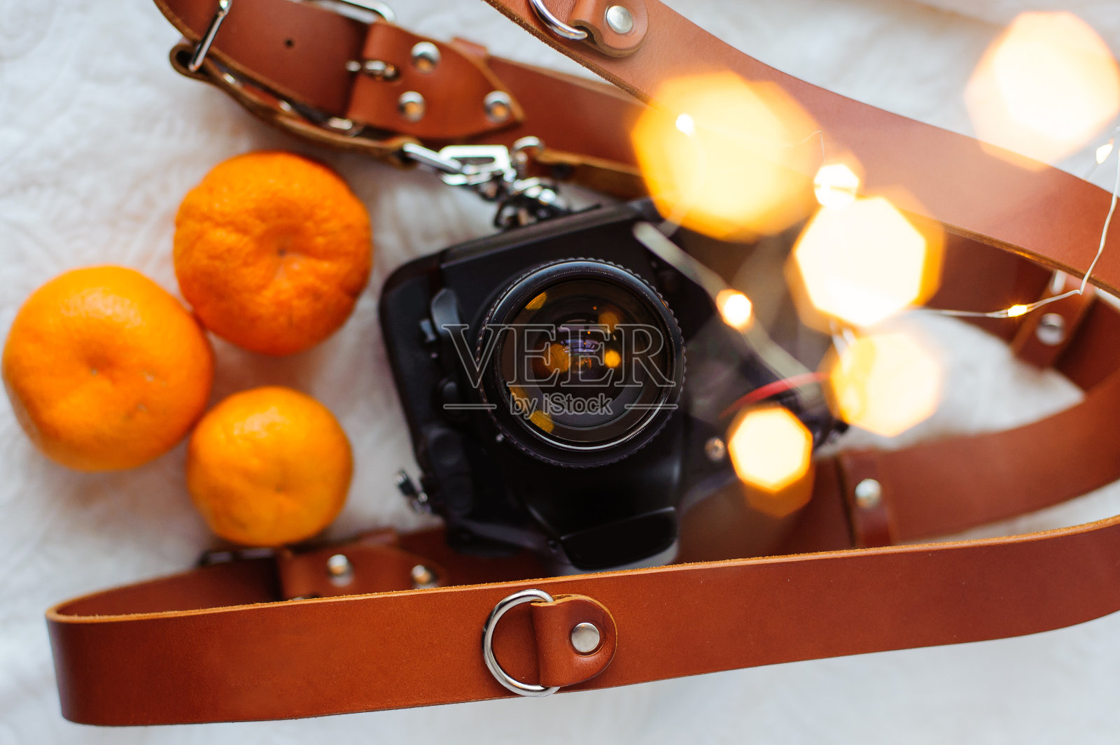 照片相机，皮带，桔子和圣诞灯的白色背景。照片摄影图片