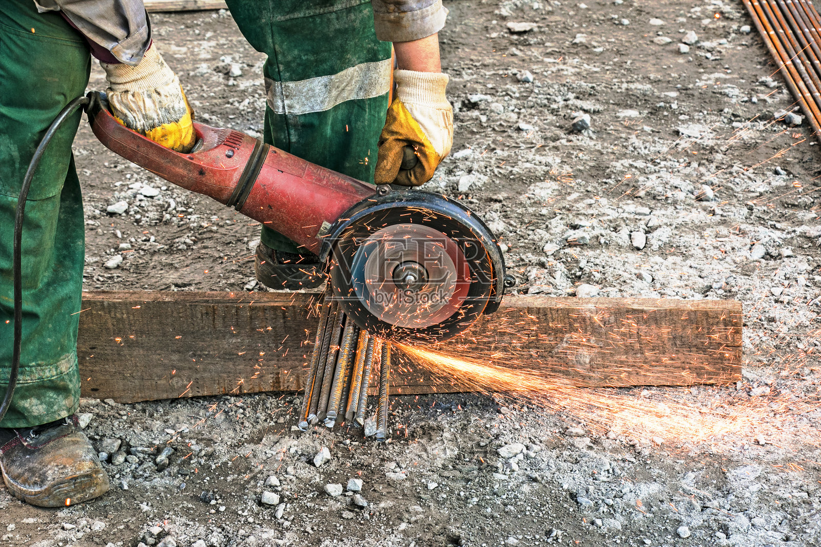 一名男子用角磨机切割钢筋。照片摄影图片