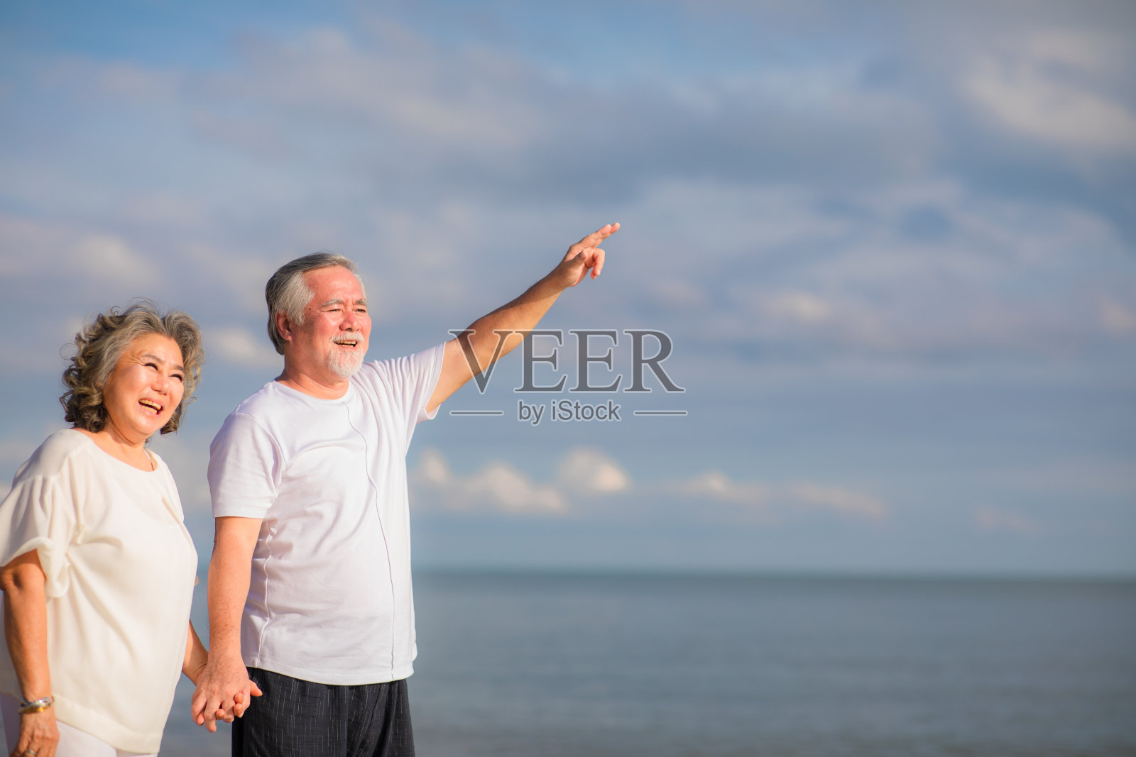 一对亚洲夫妇一起在海滩上散步。退休和度假的概念。照片摄影图片