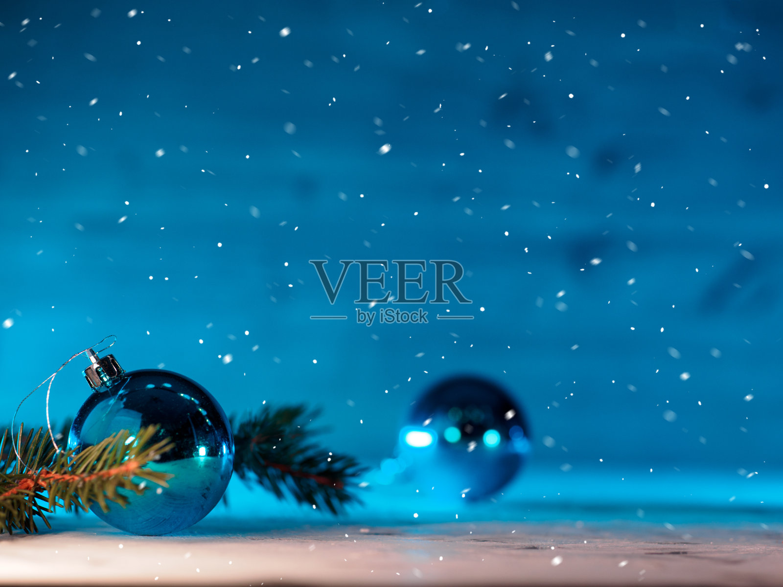 圣诞节蓝色背景，圣诞树树枝，蓝色球，飘落的雪花照片摄影图片