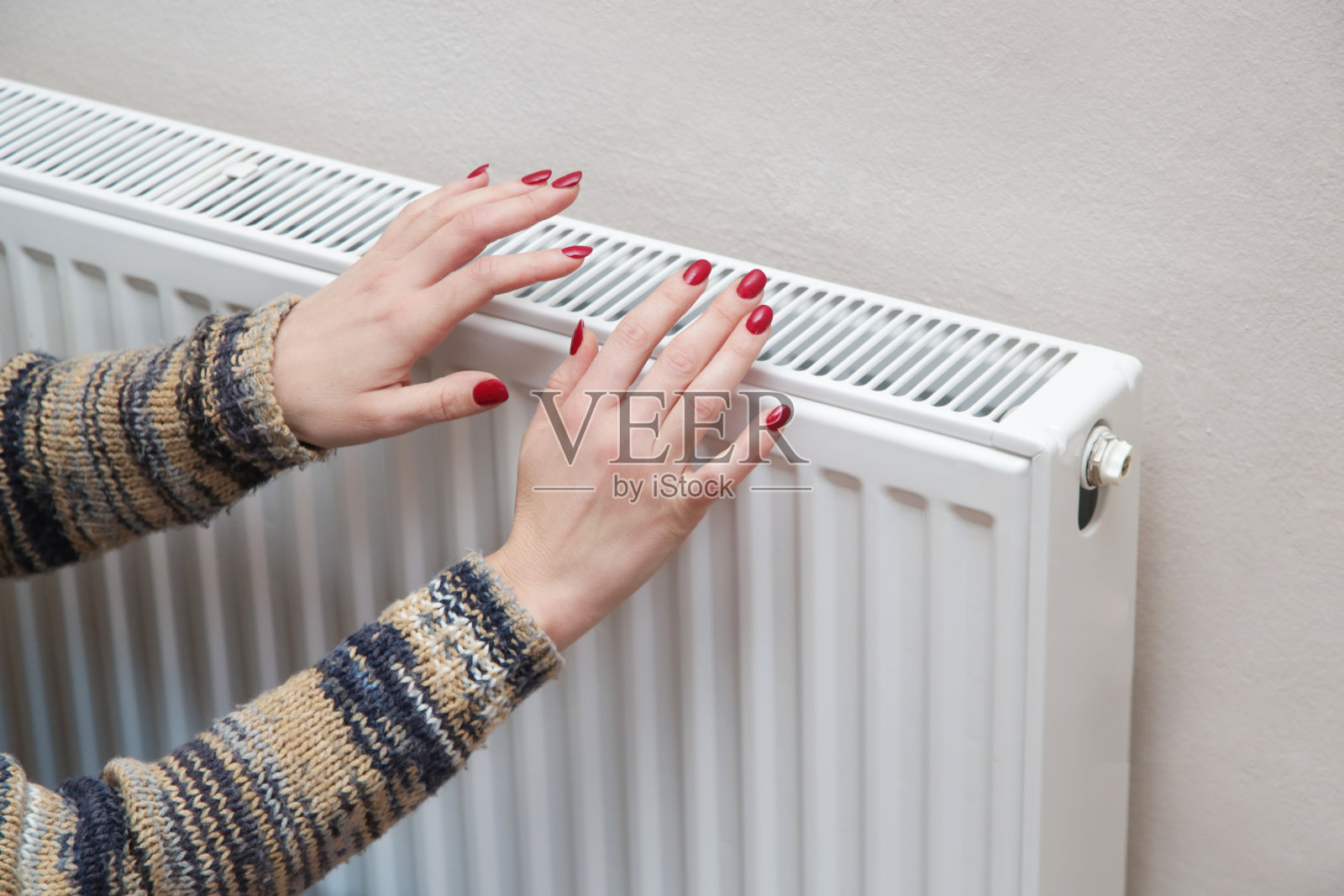 女人在暖气片上暖手照片摄影图片