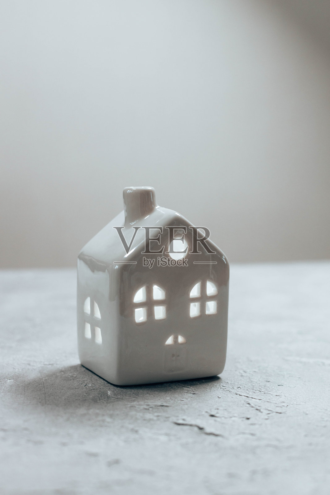 舒适的小住宅模型与雪花飘落与复制空间在灰色背景。圣诞快乐，新年作文。明亮的寒假作文。贺卡，横幅，海报照片摄影图片