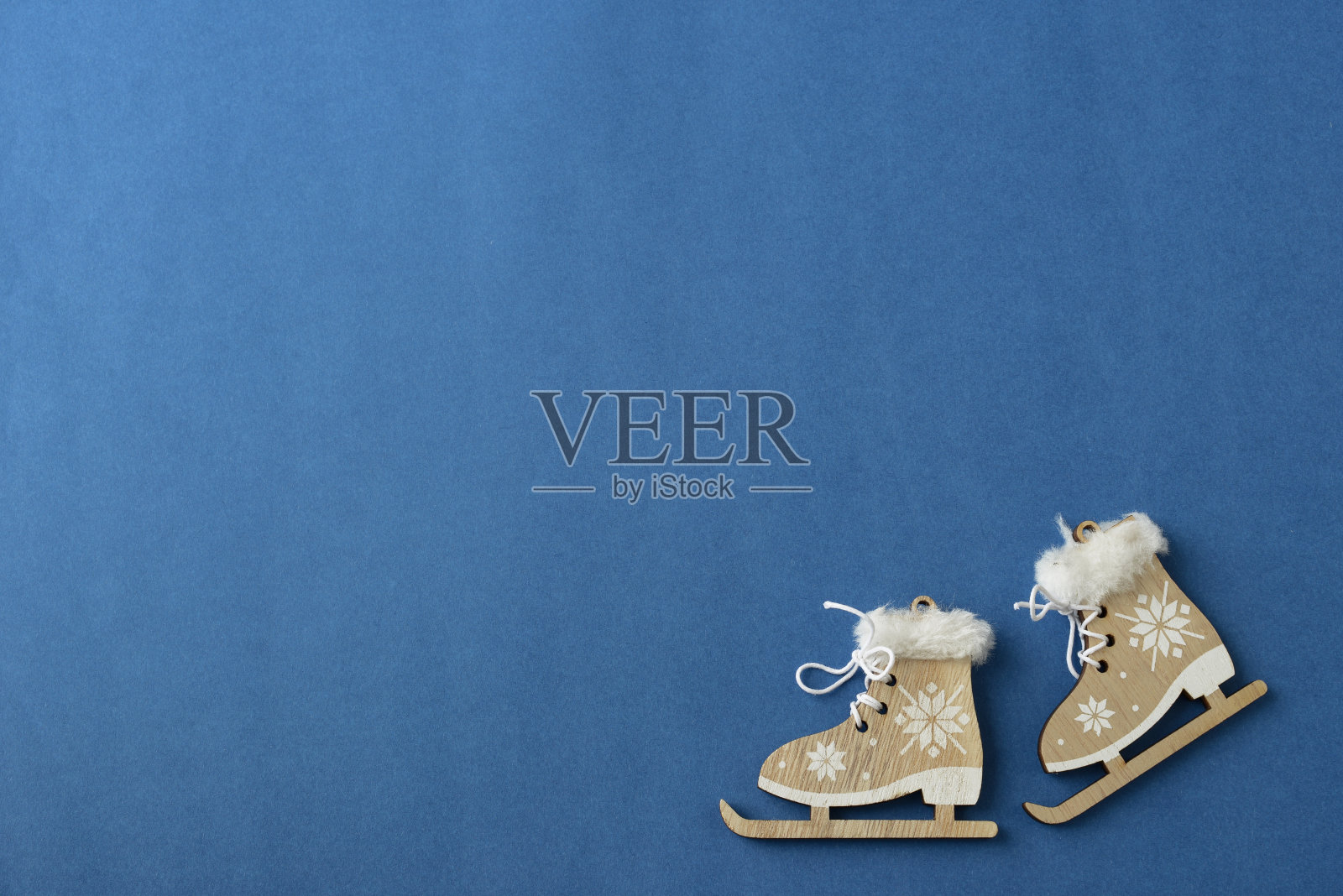 蓝色背景上的溜冰鞋，圣诞节、冬季或新年背景，带有文字和logo位置，冬季运动概念banner，圣诞树木制手工装饰品照片摄影图片