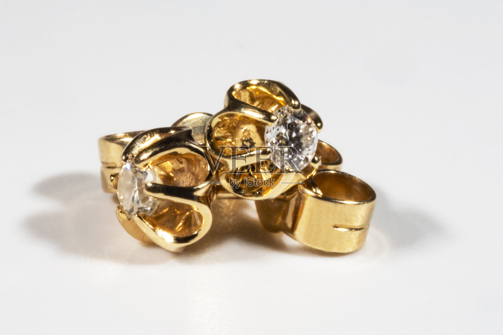 特写的黄金耳环与真正的钻石。小休闲耳环单钻石。白色背景下美丽的耳环。女性的配件照片摄影图片