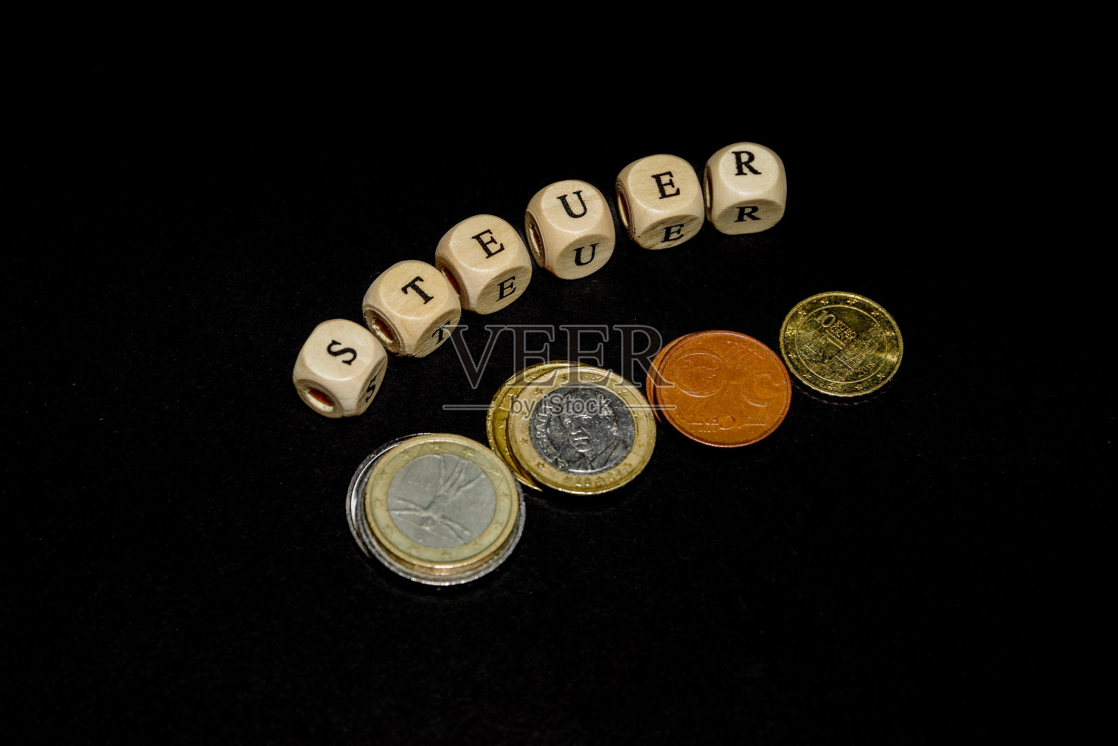 立方体上的铭文，在木制纹理的立方体上用德语写着TAX这个词，周围是硬币照片摄影图片