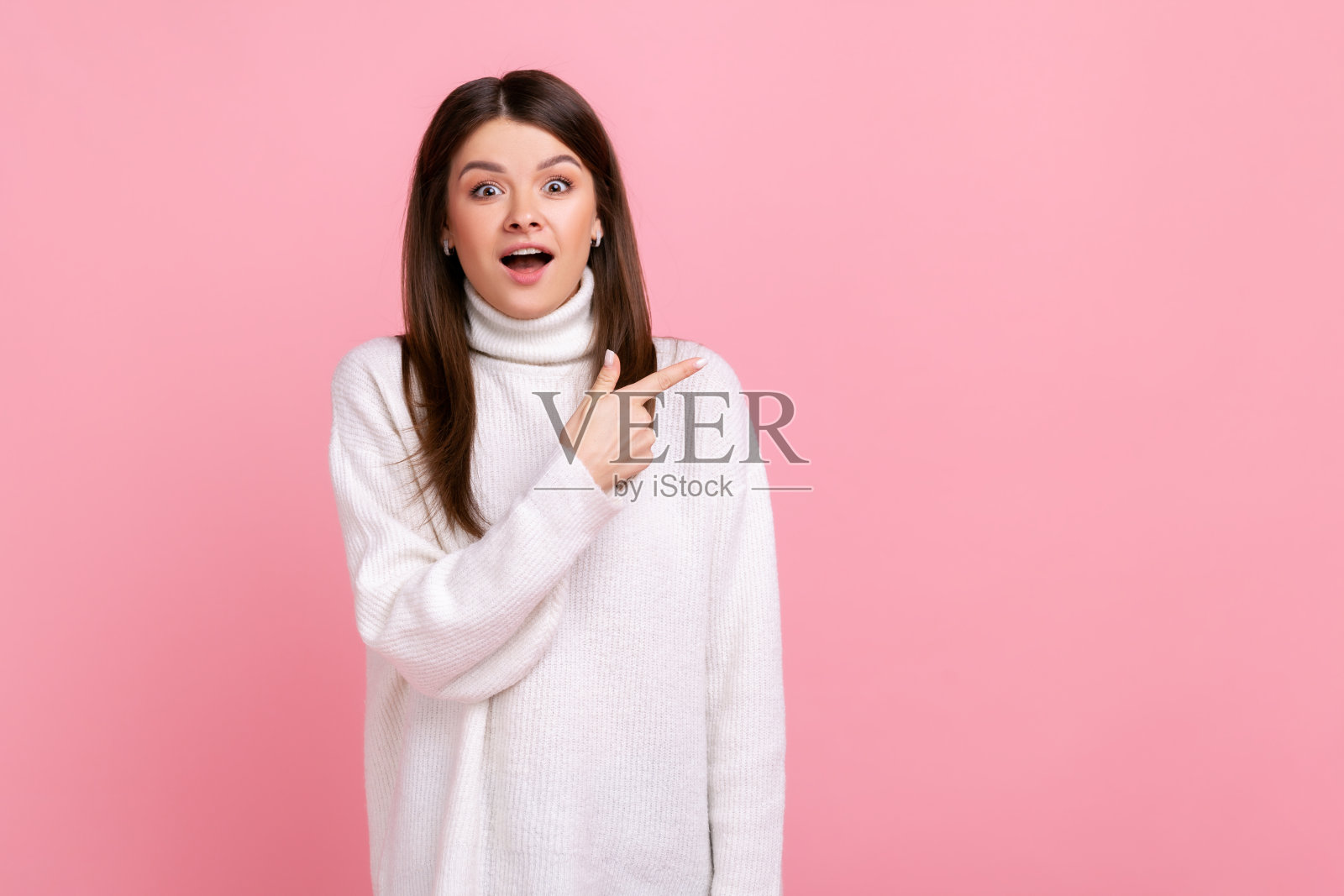 惊讶的黑发女孩的肖像在广告内容的空白处指向一边，表示惊讶。照片摄影图片