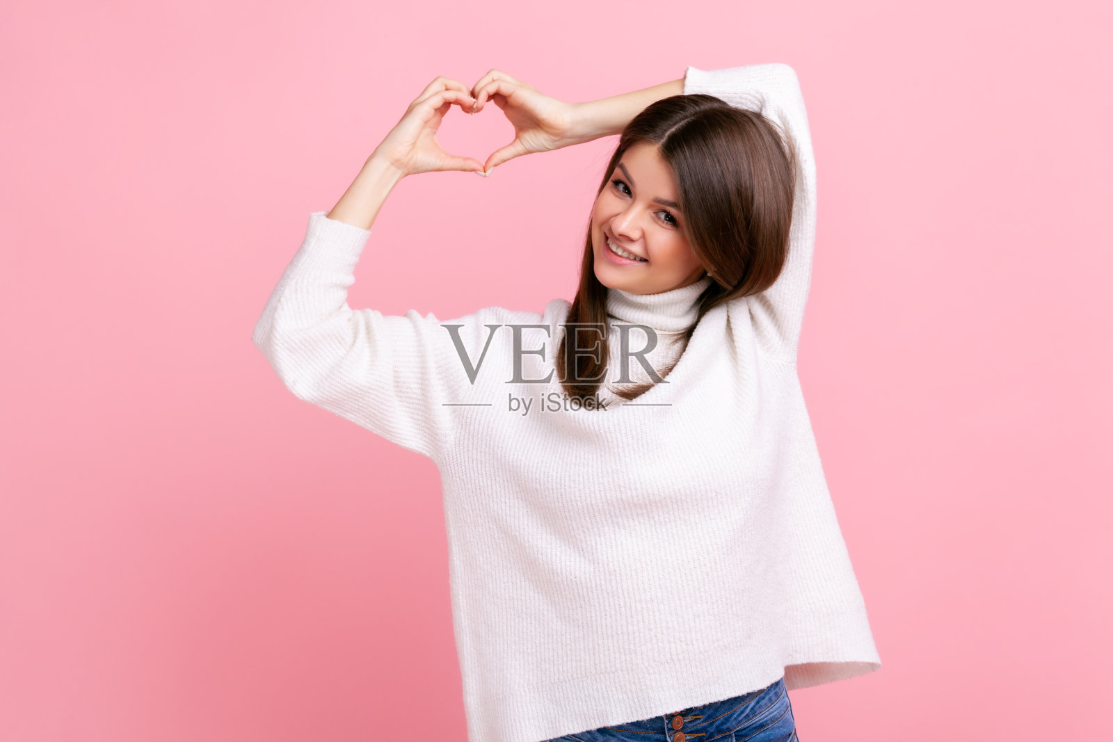 微笑美丽的女性用手做心形，表达爱，友谊和关心，浪漫。照片摄影图片