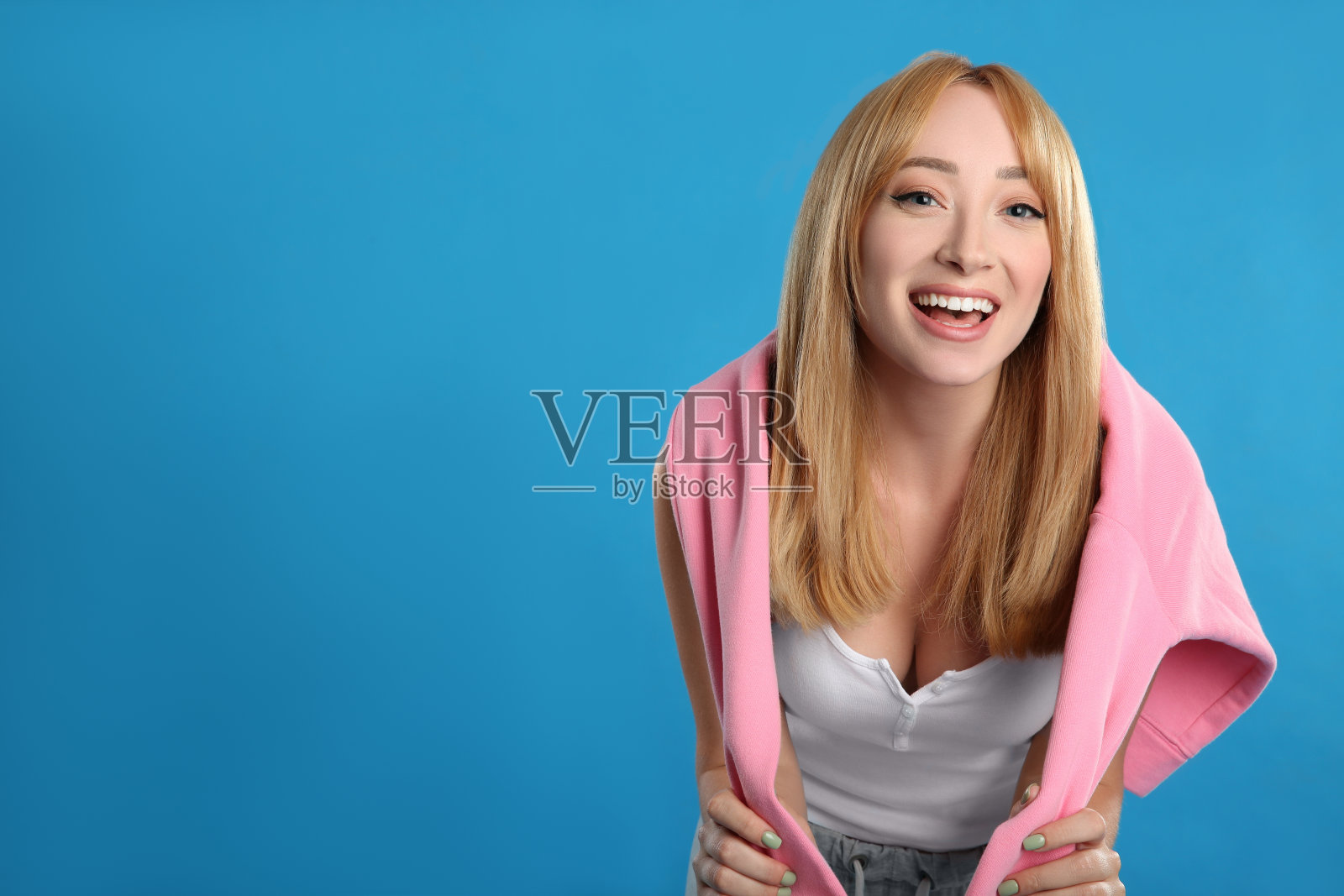 美丽的年轻女子，金发碧眼，蓝色背景。空间的文本照片摄影图片