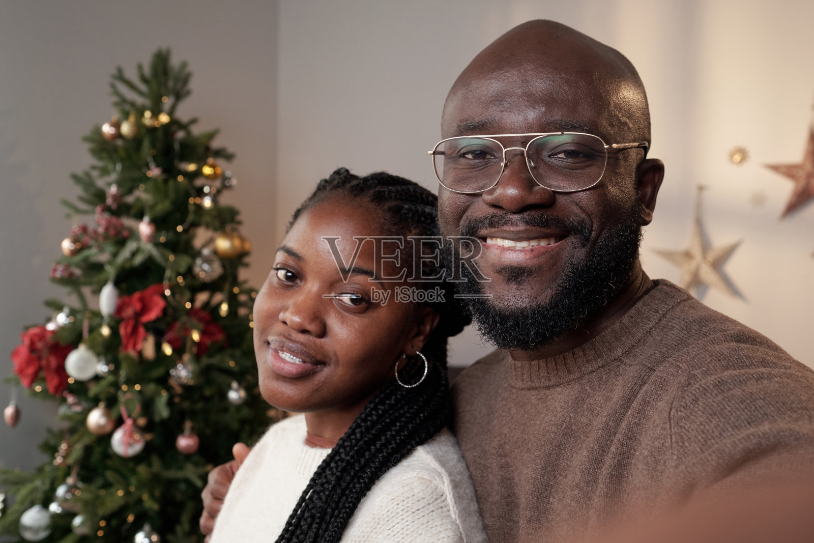 穿着便服的年轻情侣站在装饰好的圣诞树前照片摄影图片