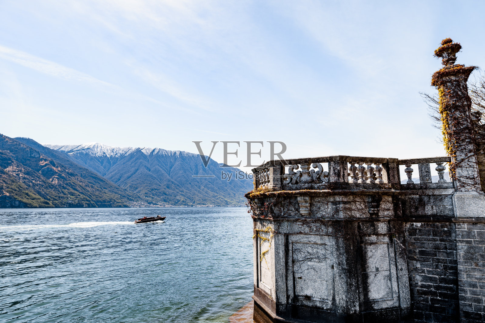 一艘游艇在科莫湖上航行，背景是带栏杆的石栅栏。意大利照片摄影图片