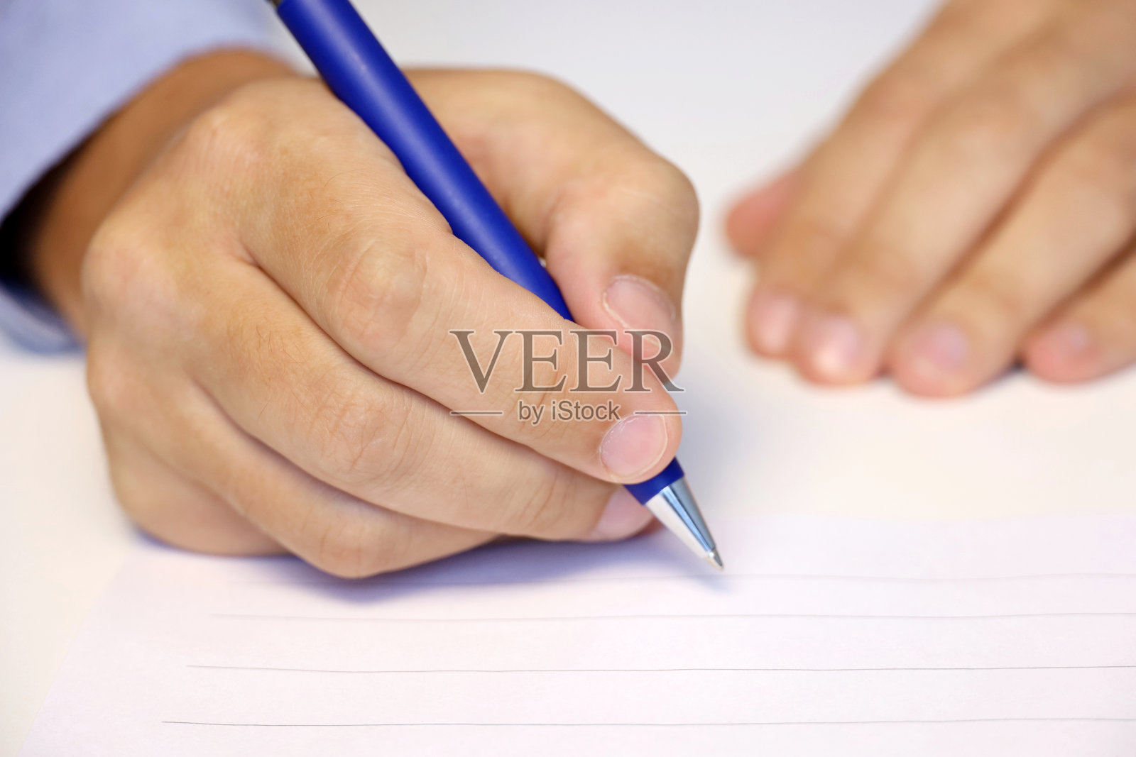 手拿笔的男人，穿蓝衬衫的男人在纸上签名照片摄影图片