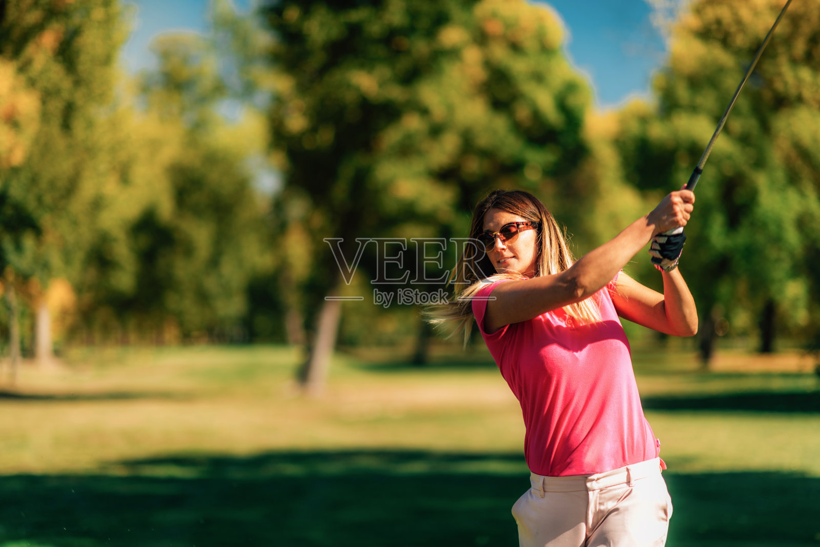一名女子在一个阳光明媚的日子里打高尔夫球照片摄影图片