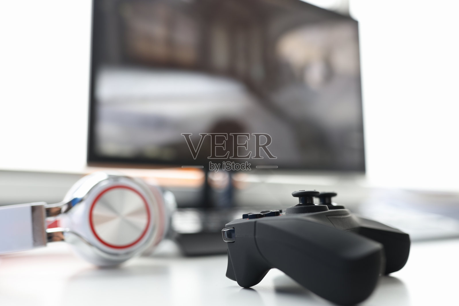 游戏手柄与耳机躺在桌子上与电脑显示器的特写照片摄影图片