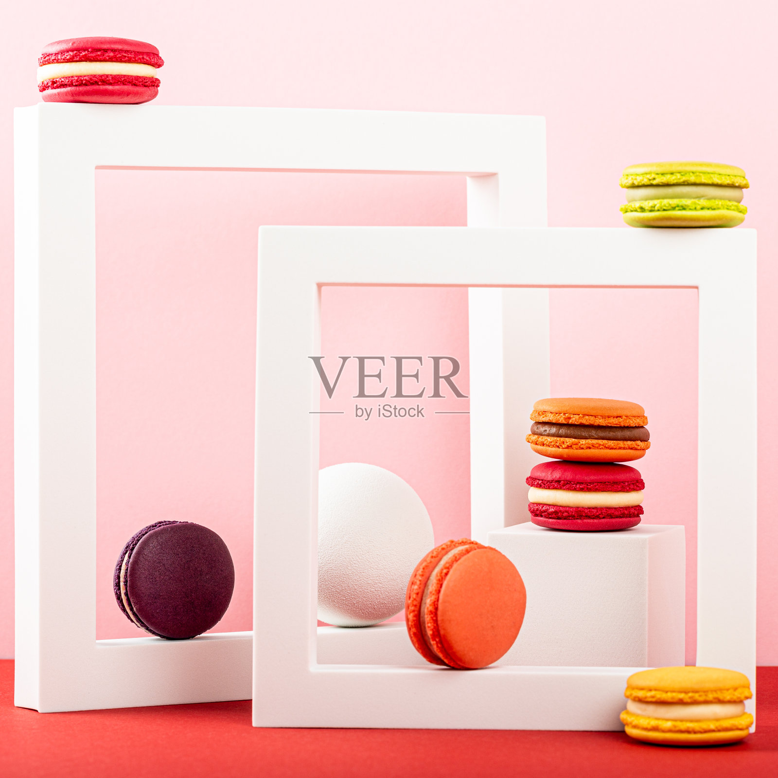 彩色的法国马卡龙甜点。一套不同口味和颜色的马卡龙饼干与方形形状在粉红色的背景。带有复制空间的节日贺卡概念照片摄影图片