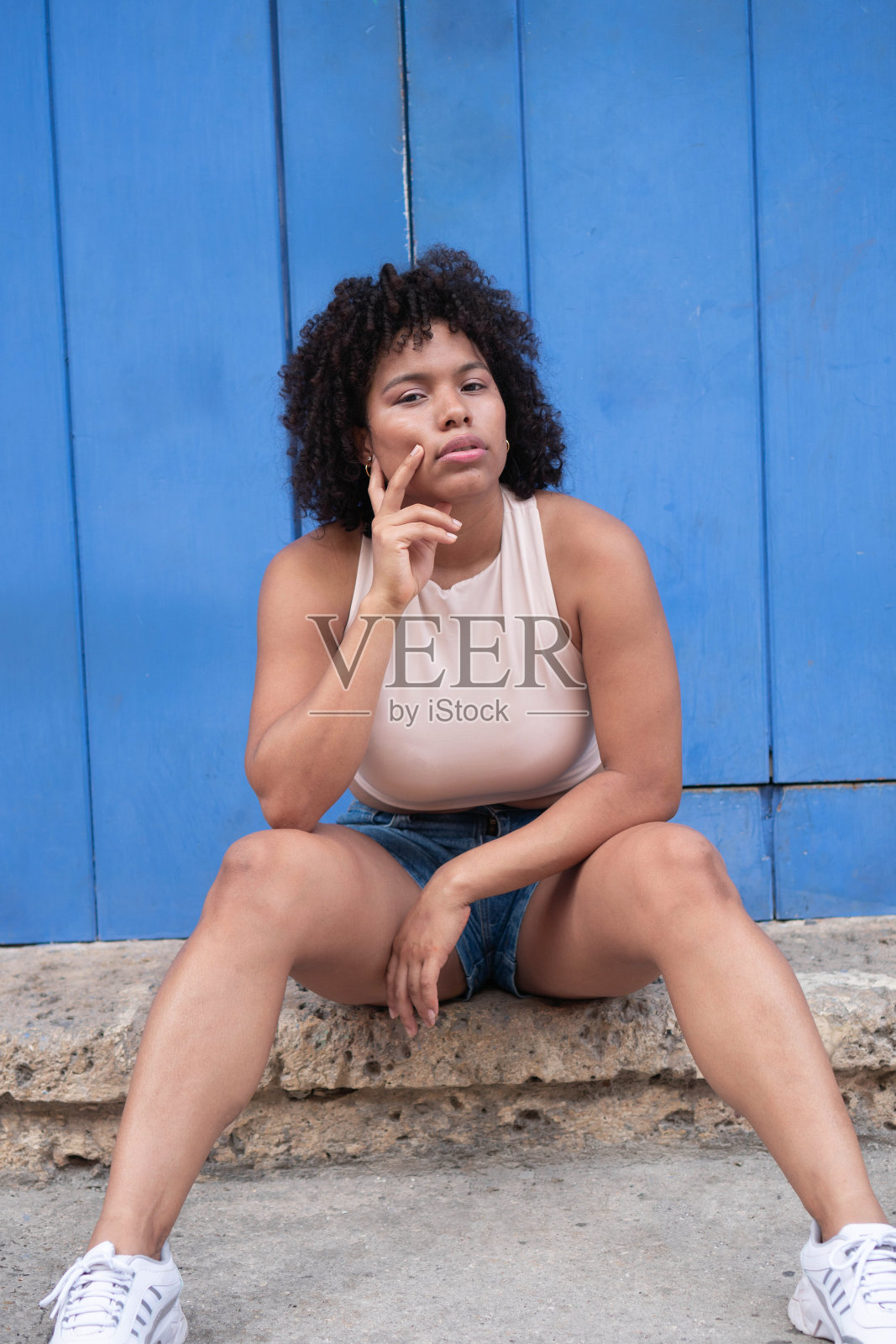 美丽的混合种族妇女与自然非洲式头发自信地坐在街上。照片摄影图片