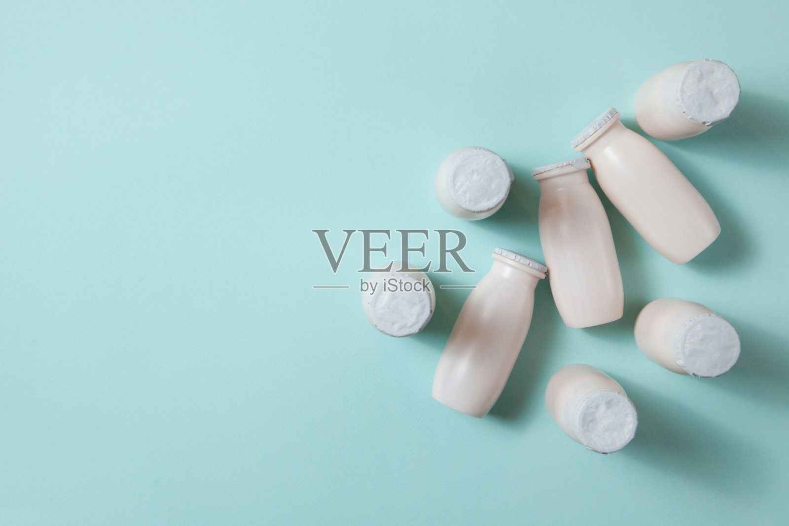 瓶子与益生菌和益生元牛奶饮料在浅蓝色的背景。照片摄影图片