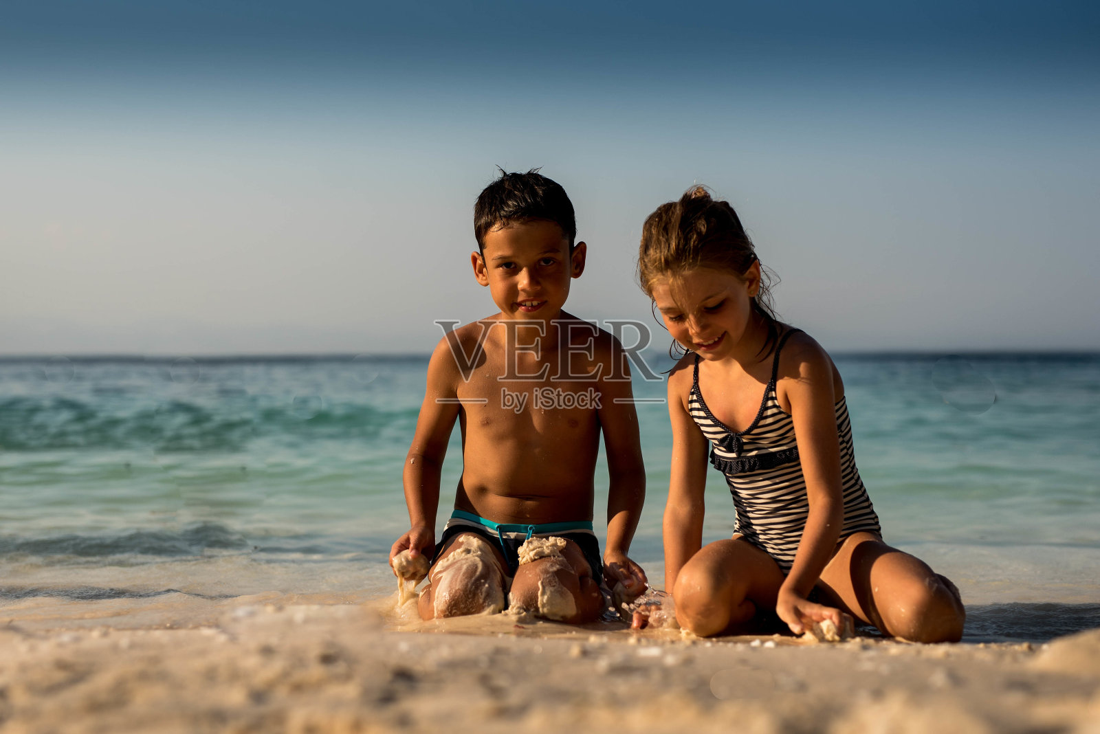 两个孩子在沙滩上玩耍照片摄影图片