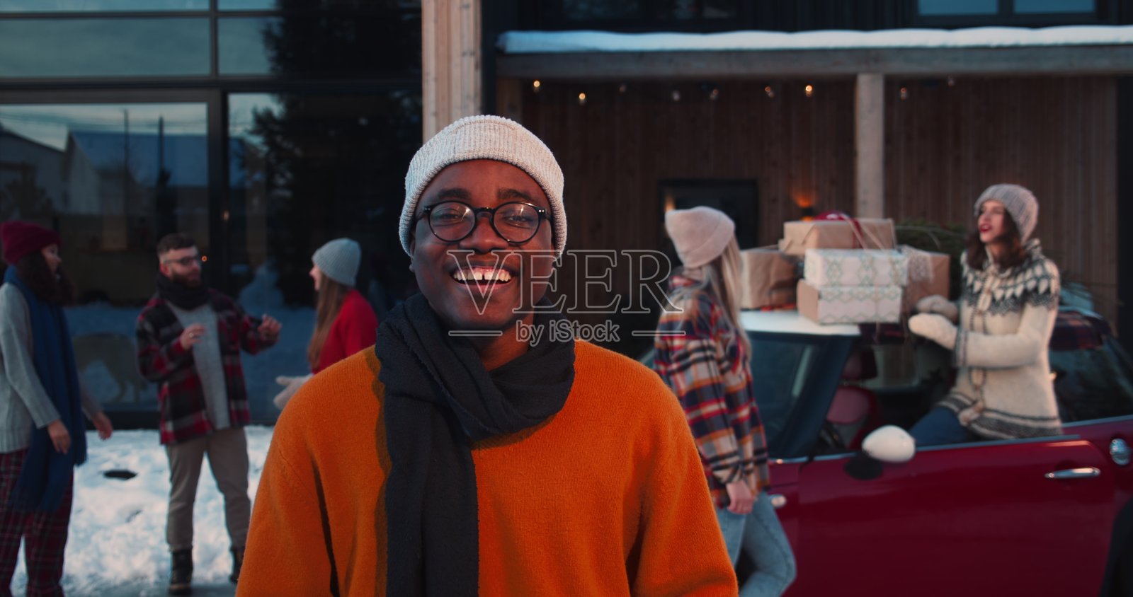 快乐微笑的年轻非洲裔美国人在冬季帽子，眼镜微笑的相机在有趣的圣诞晚会慢动作。照片摄影图片