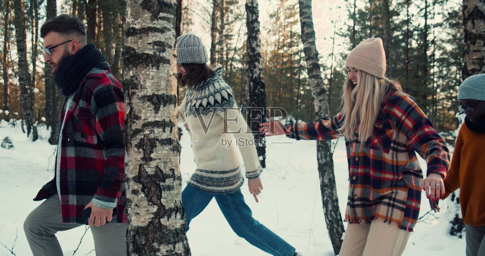 一群快乐的多民族朋友沿着雪冬森林小路散步，一起享受欢乐的假期周末慢动作。照片摄影图片
